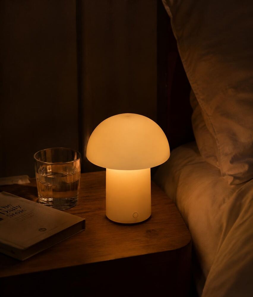 The Glow lamp lit warmly on a bedside table at night